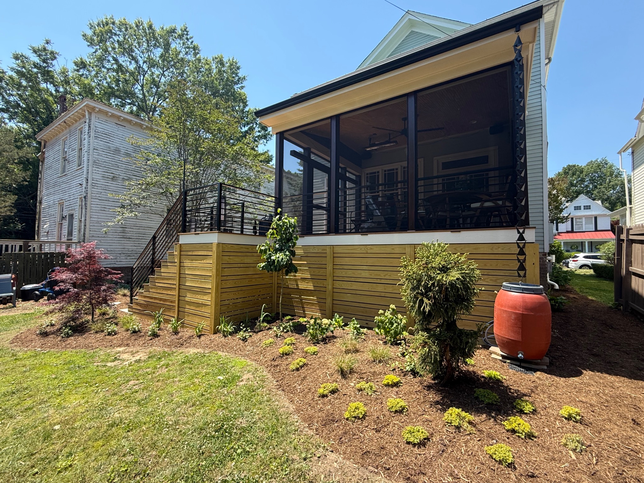 Finished screened porch exterior with custom railings and landscaped yard