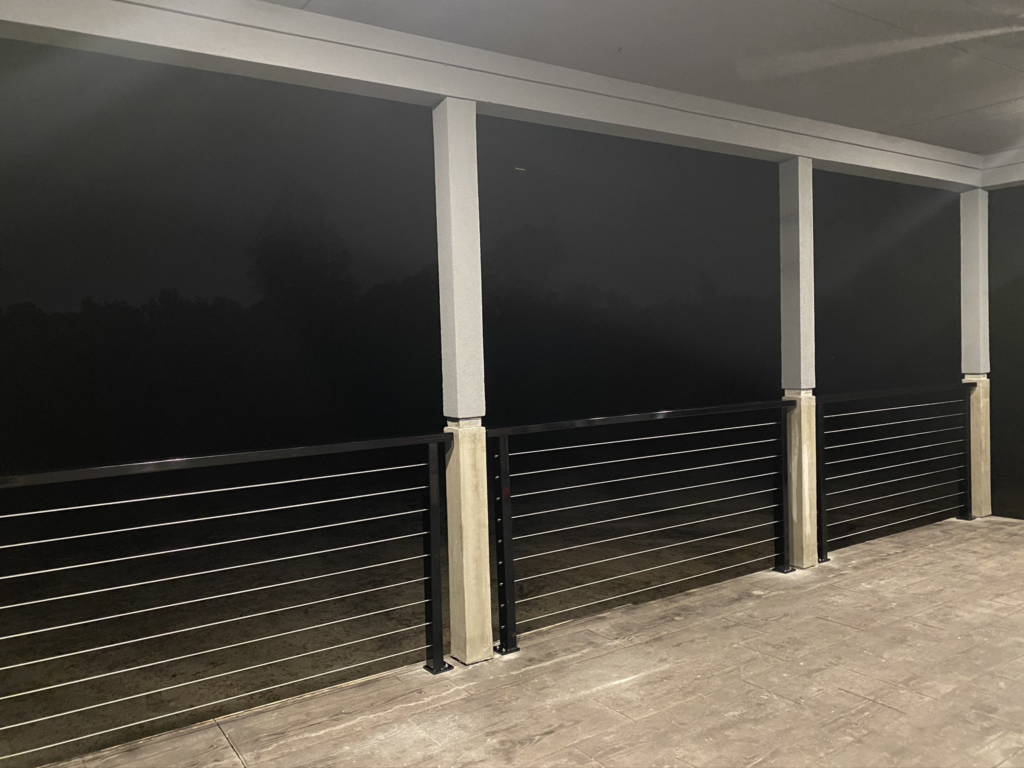 Finished covered porch with black horizontal cable railing