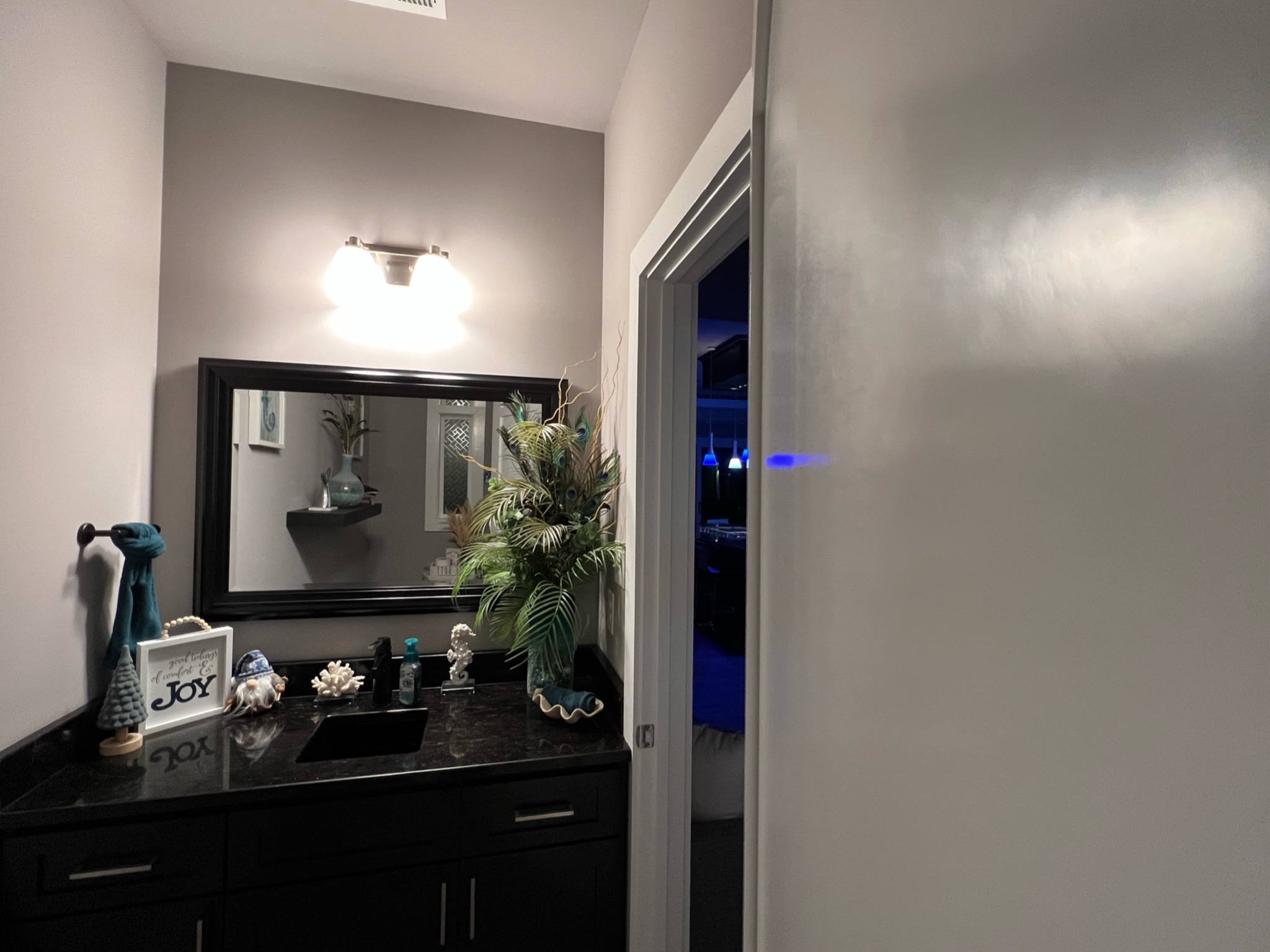 Finished powder room with dark cabinetry and stone countertop