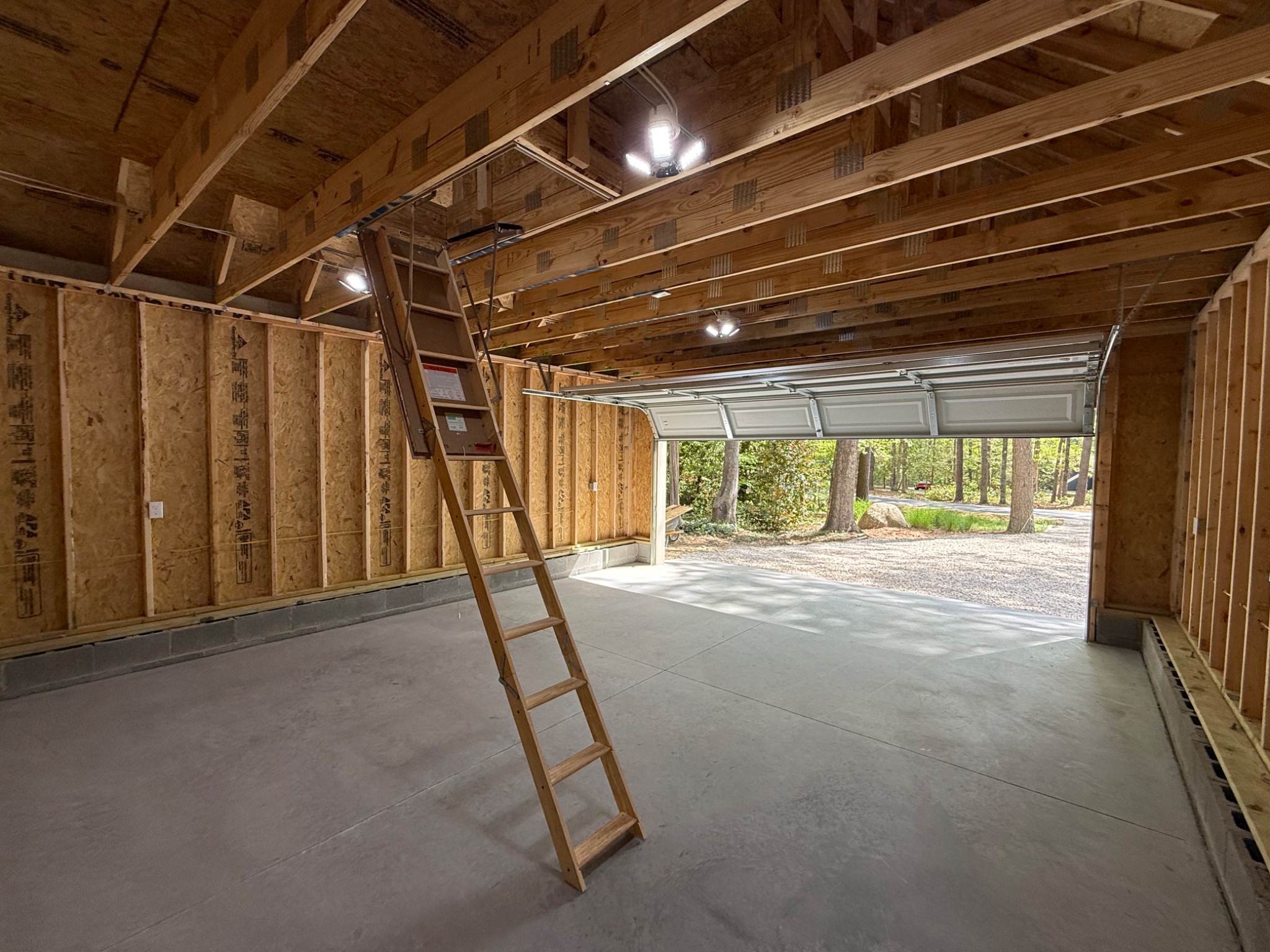 Interior of detached garage showing framing electrical lighting and garage door