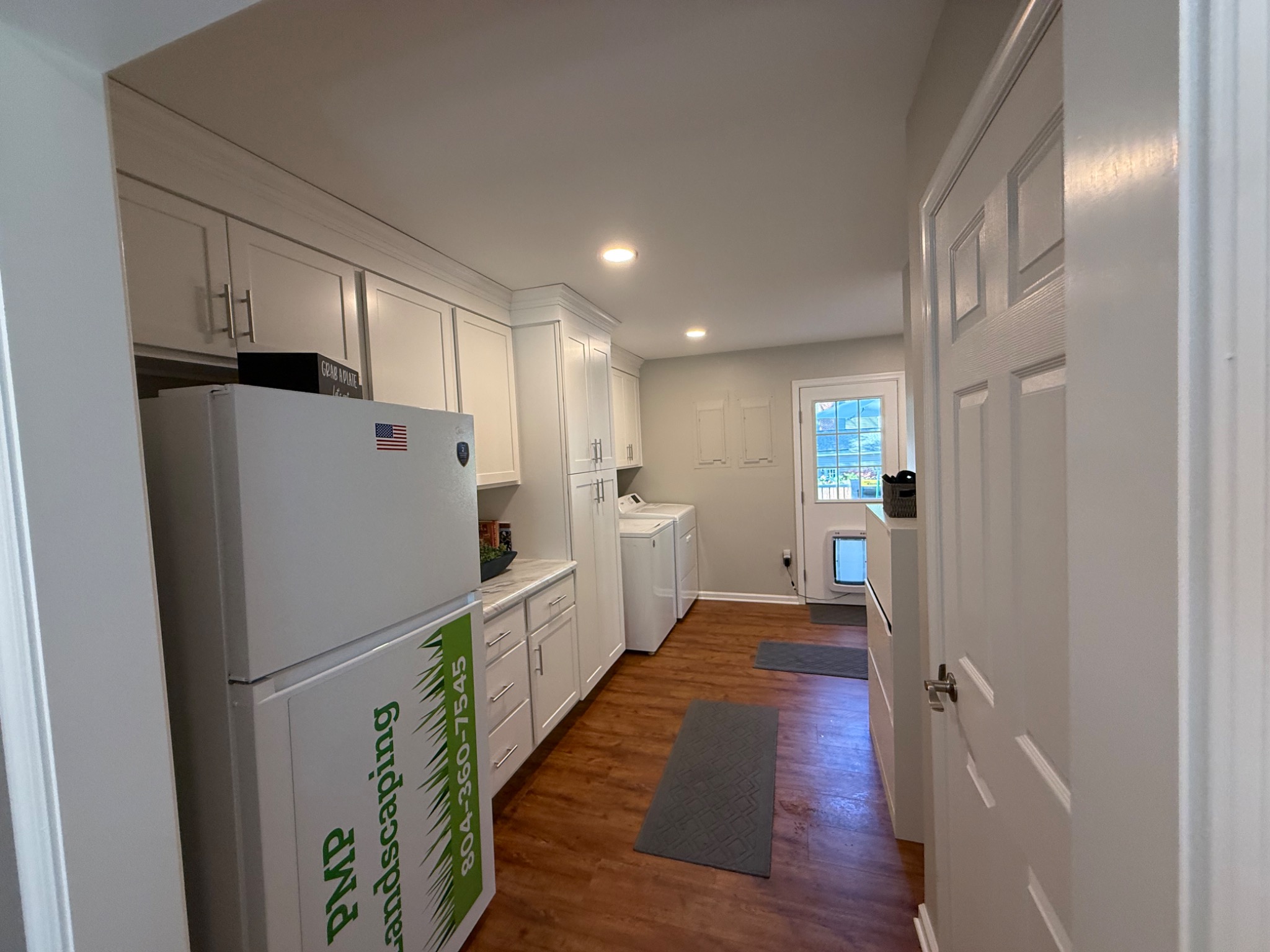 Finished full-height white cabinetry and laundry storage in converted room