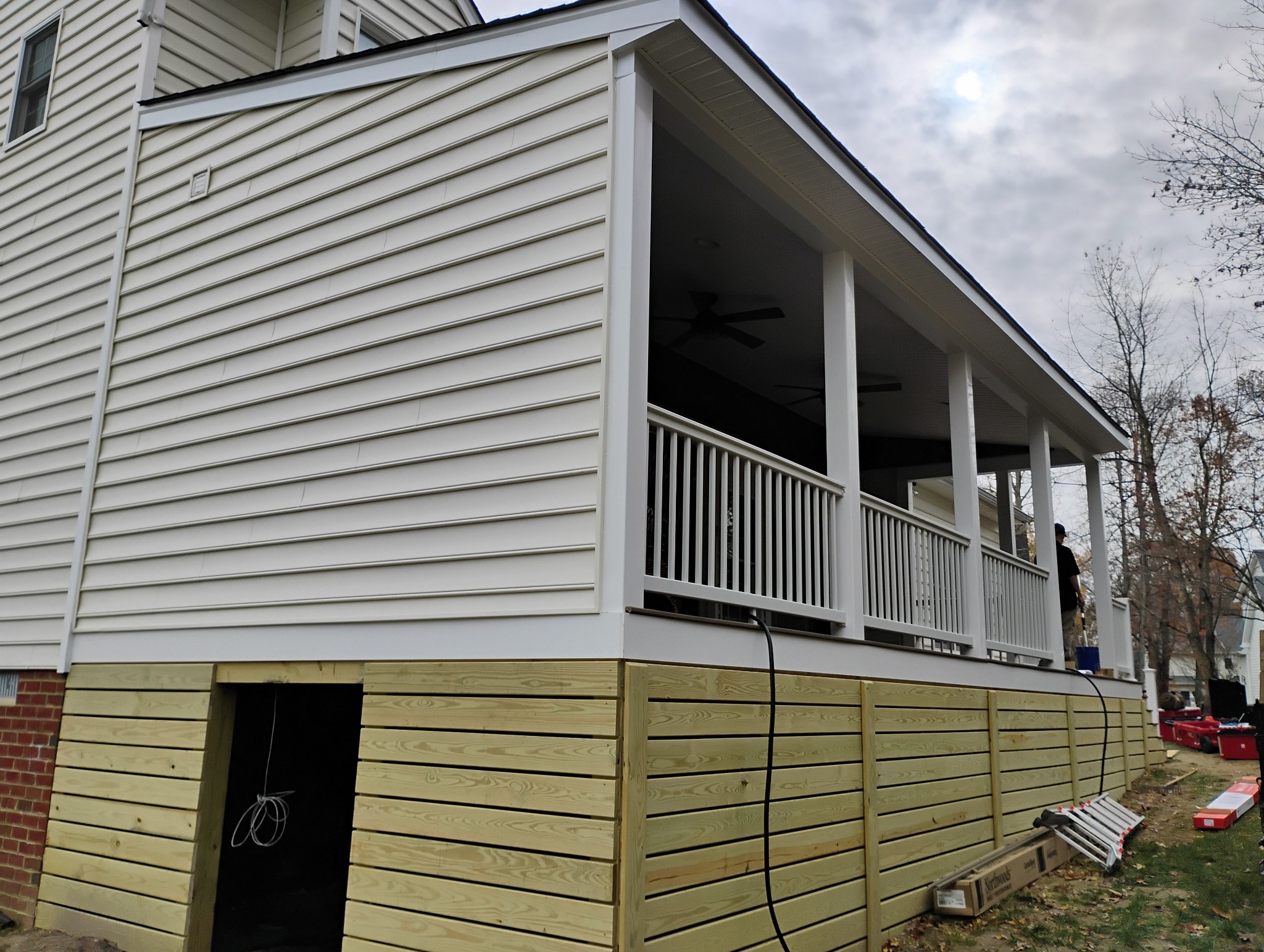 Screened porch nearing completion with finished railings and under-deck skirting