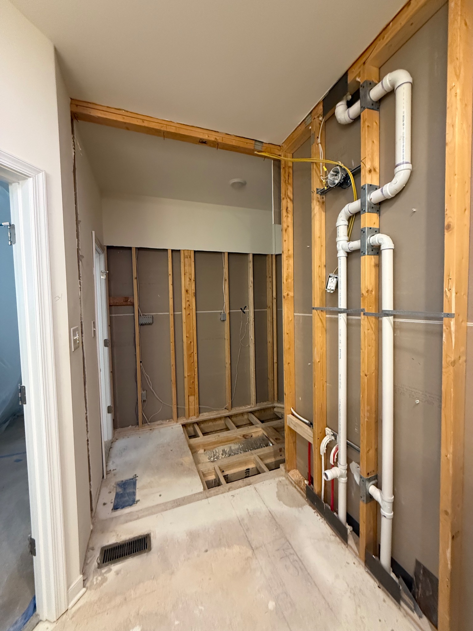Primary bathroom opened to framing with plumbing exposed during renovation