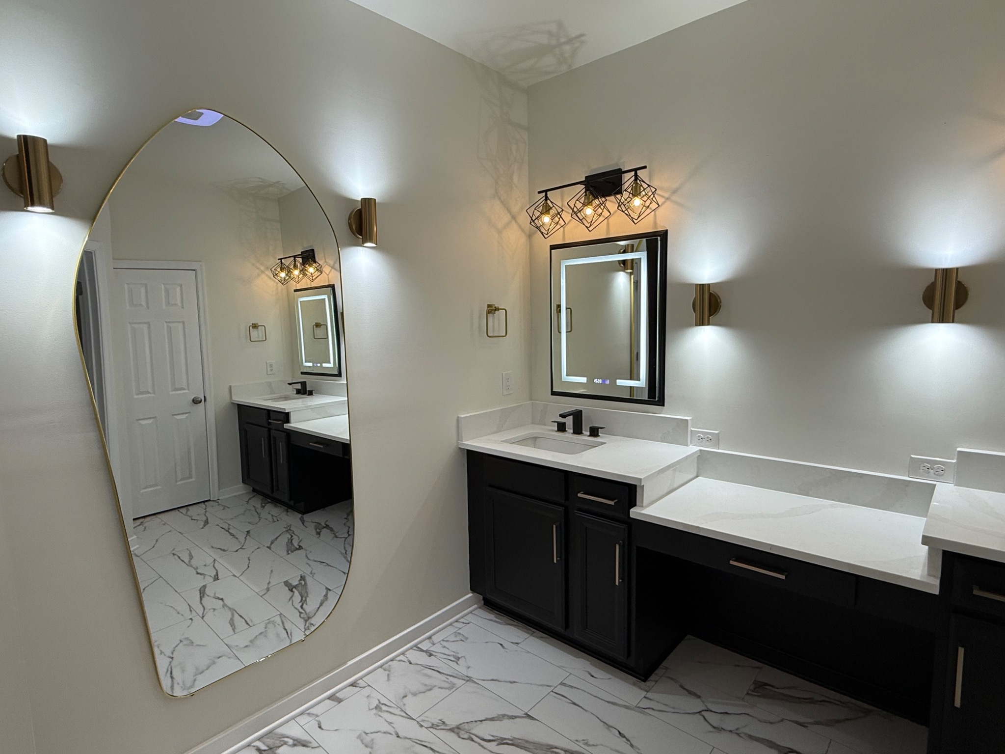 Finished primary bathroom with sculptural full-length mirror and modern vanity