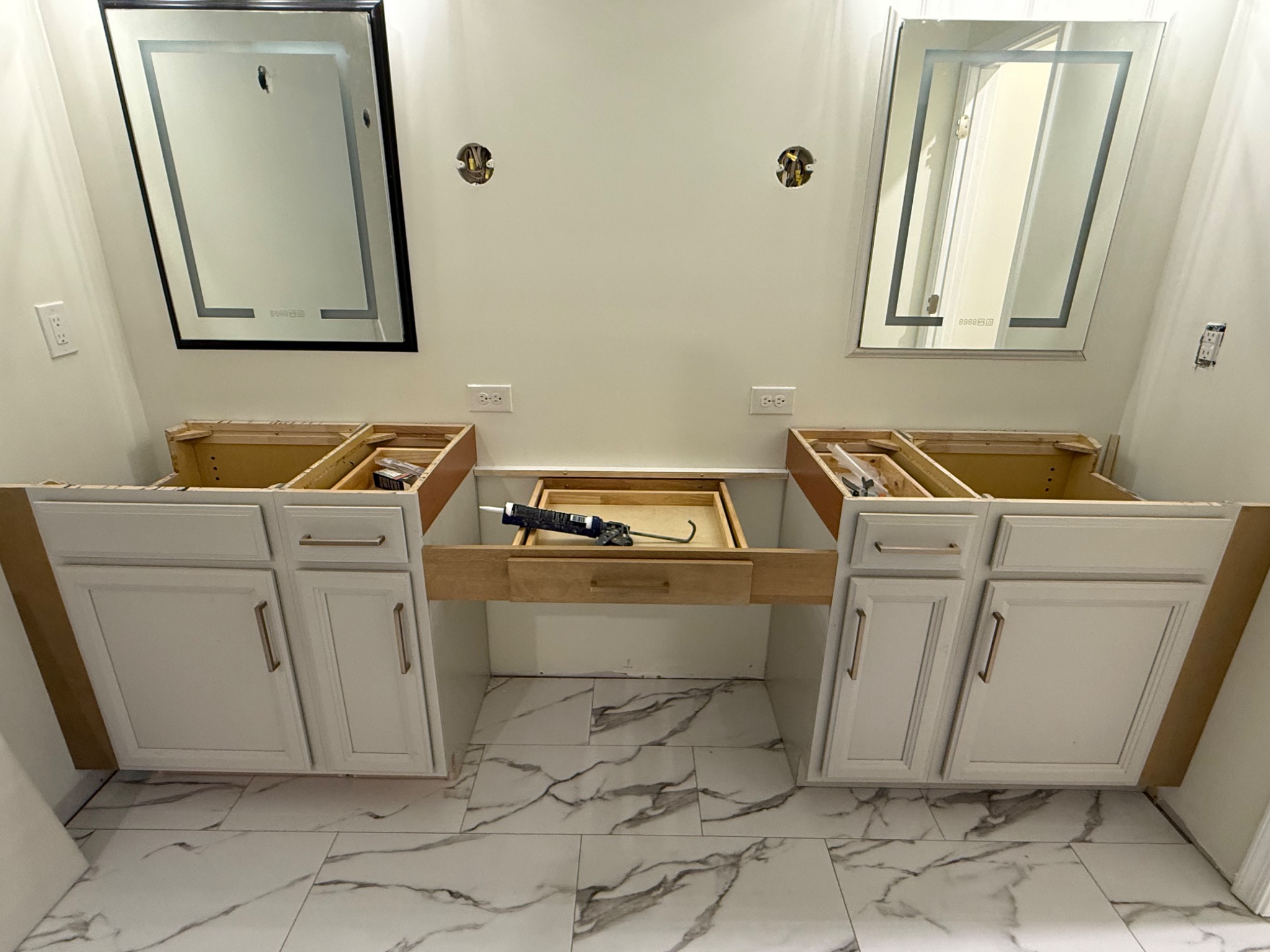 Double vanity cabinets and marble-look floor tile being installed