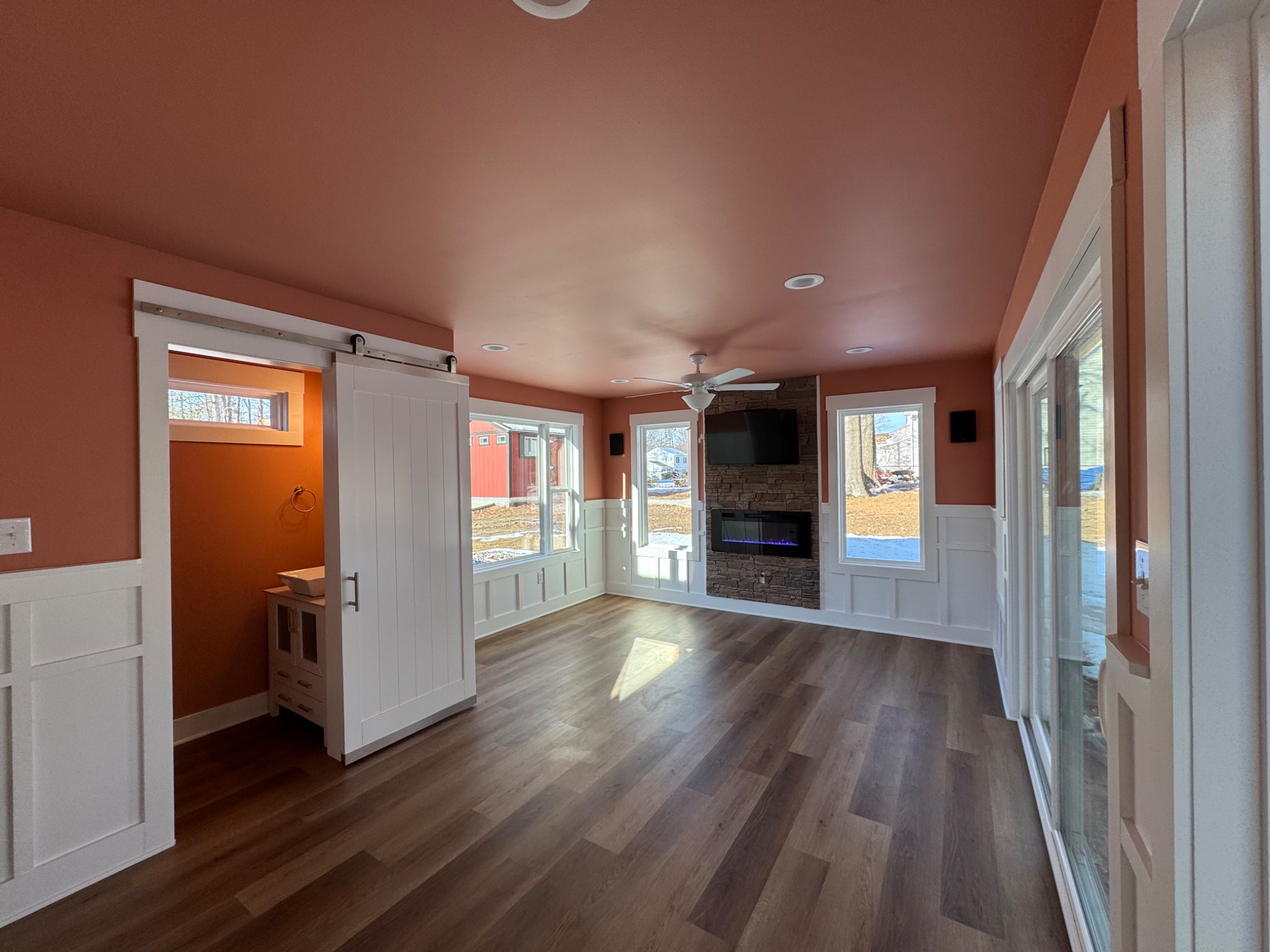 Finished sunroom interior with fireplace, windows, and custom wainscoting